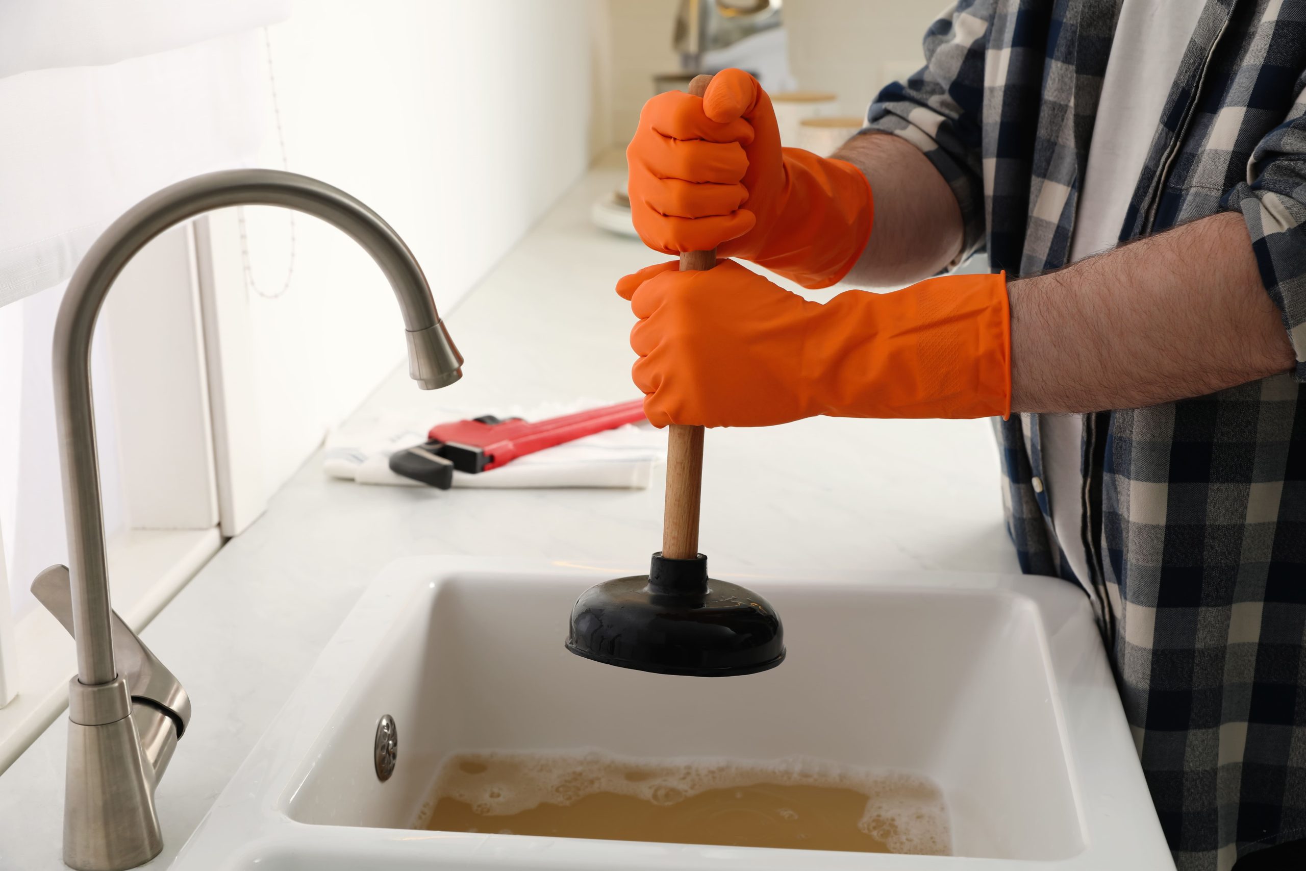 man-using-plunger-to-unclog-sink-drain-in-kitchen-2026-01-19-16-13-11-utc